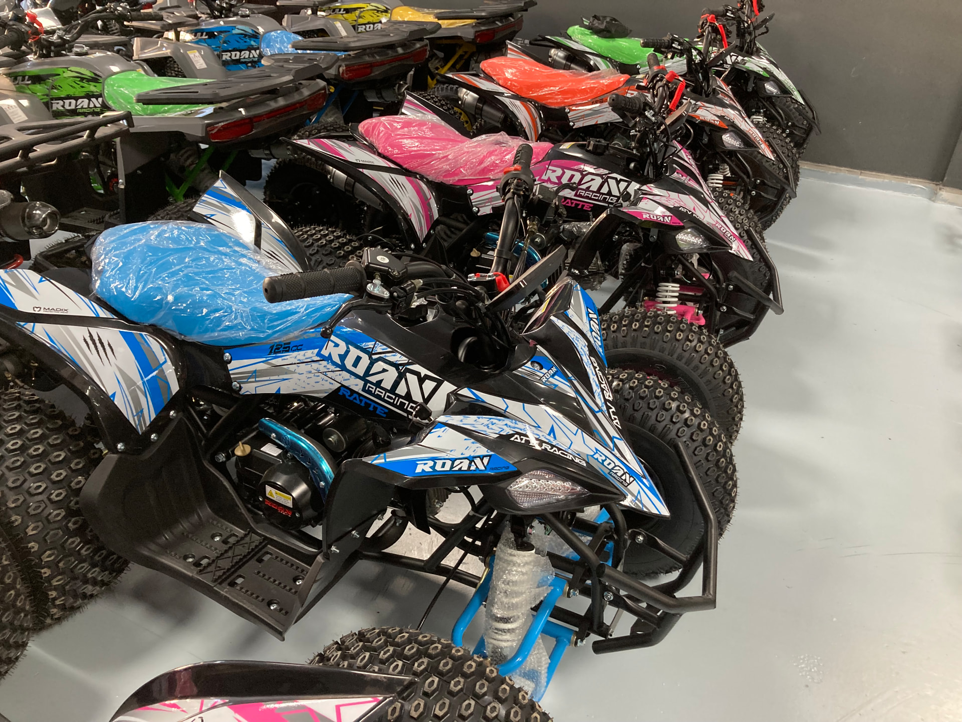 Quads ROAN Racing Ratte 125cc en azul, blanco y rosa expuestos en fila